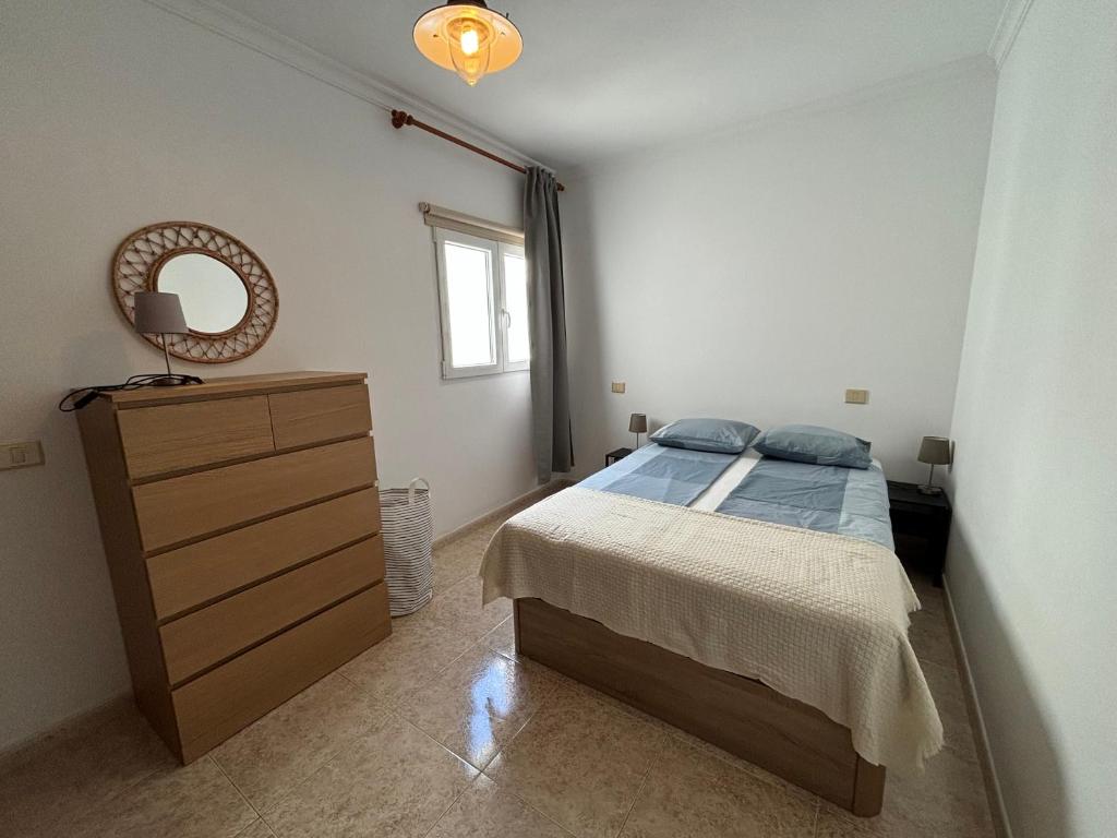 a bedroom with a bed and a dresser and a mirror at MarMontaña in Arinaga