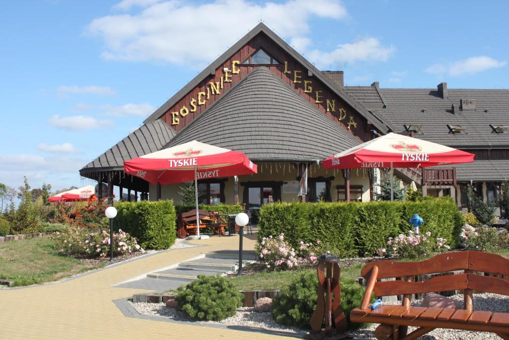 ein Restaurant mit Sonnenschirmen und einer Bank davor in der Unterkunft Gościniec Legenda in Wyszogród