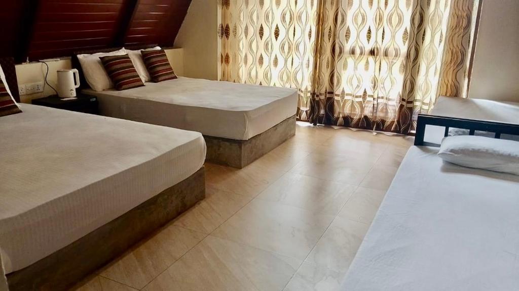 een hotelkamer met 2 bedden en gordijnen bij Coco Breeze Cabanas - free Airport pick up or drop off in Katunayaka