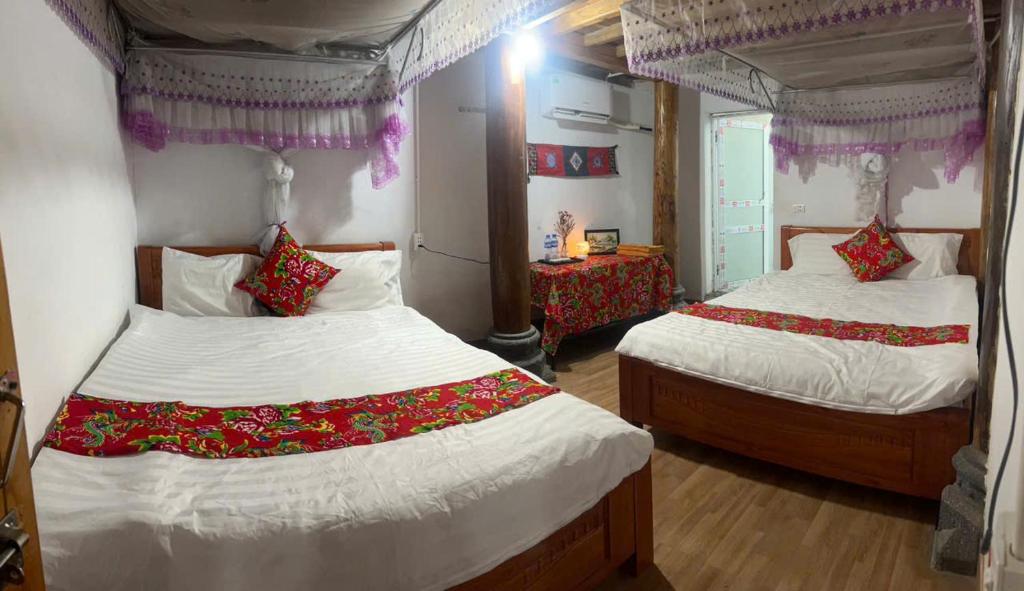a bedroom with two beds with white sheets and red pillows at Đoàn Kết Homestay in Dồng Văn