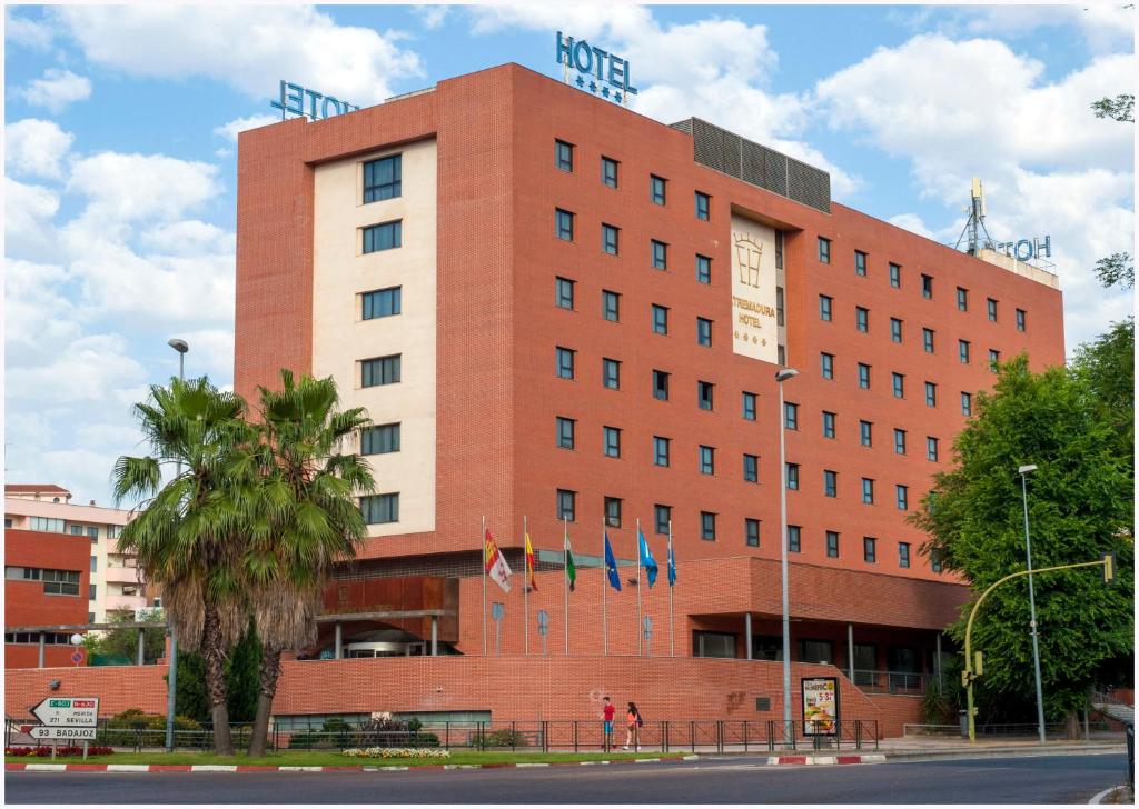 un gran edificio rojo con banderas delante en Extremadura Hotel, en Cáceres