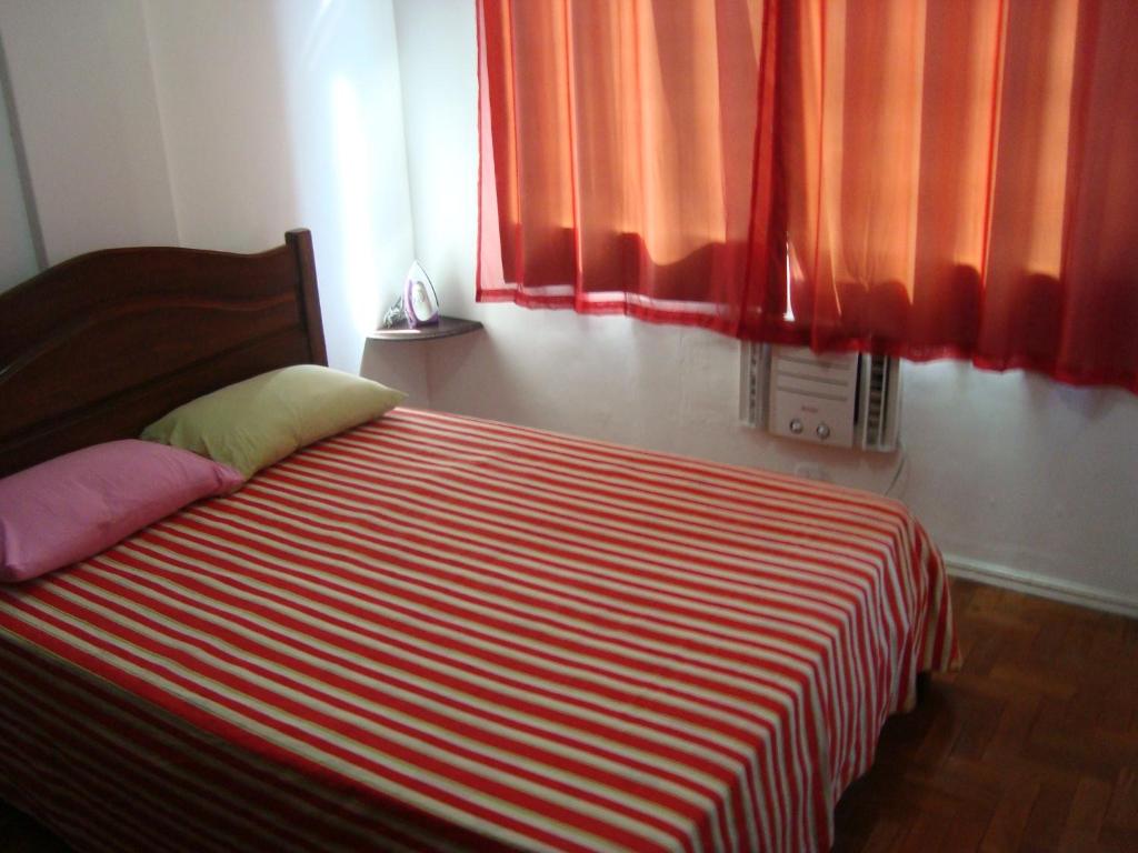 1 cama con manta de rayas roja y blanca en una habitación en Apart Marcelo - Copacabana, en Río de Janeiro