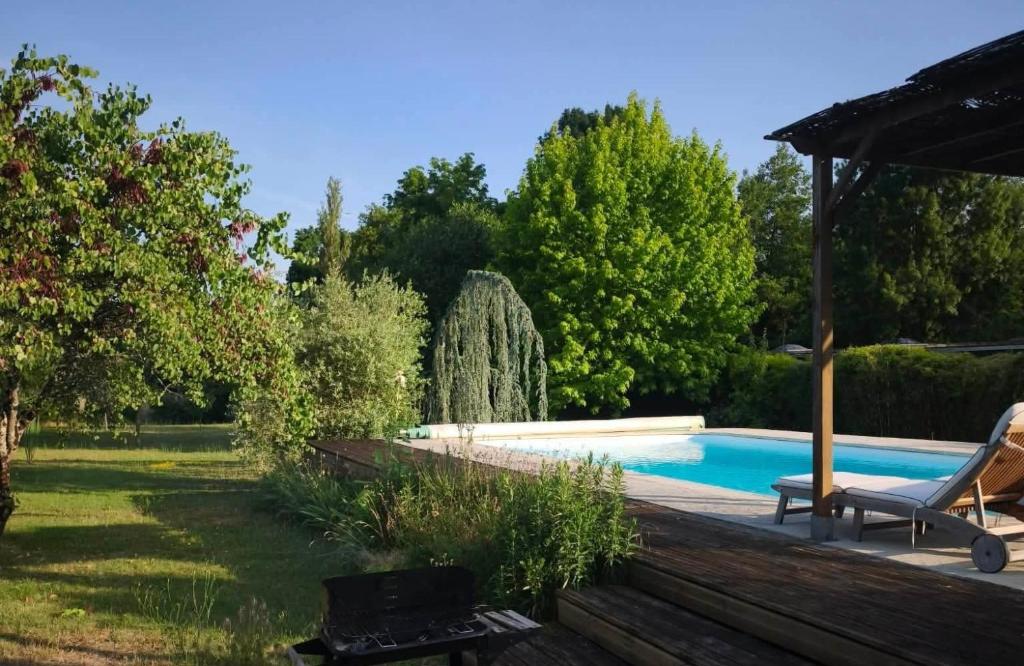a swimming pool in a garden with a chair next to it at Le Jardin des Oiseaux in Saint-Michel-sur-Loire