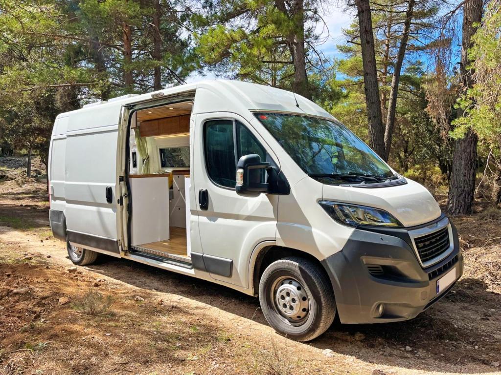 Een witte bestelbus met open deur geparkeerd in het bos. bij Glamping converted van with bathroom in Los Cristianos