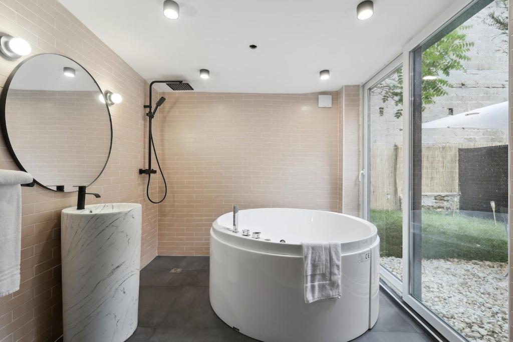 une salle de bain avec une grande baignoire et un miroir dans l'établissement Maisons Alfort 6 Luxurious little house with private garden and Jacuzzi, à Maisons-Alfort