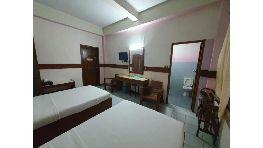 a bedroom with a bed and a desk and a mirror at โรงแรมเอเซีย in Sathani Phitsanulok