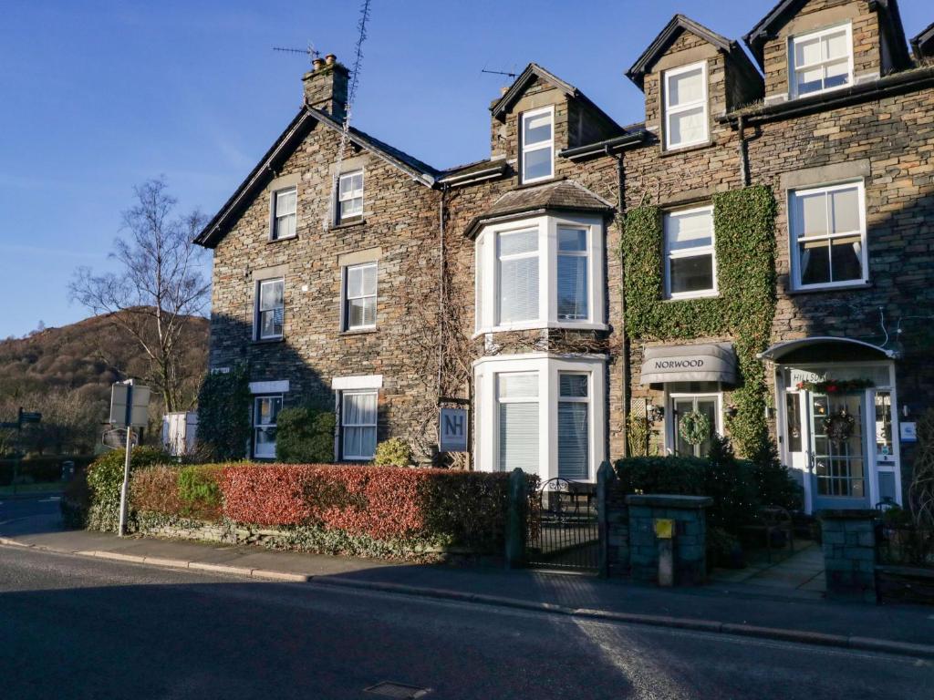 a brick house with white windows and ivy at Norwood House in Ambleside