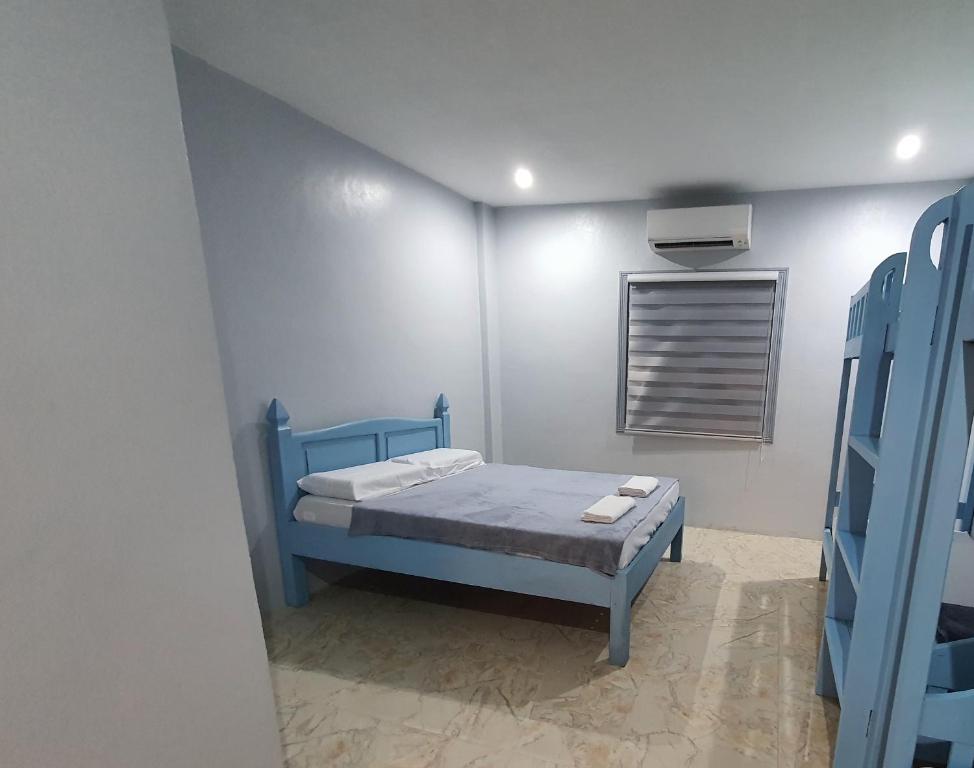 a bedroom with a blue bed and a window at Denzel's Cosy Inn in San Juan