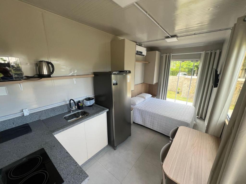 a kitchen with a refrigerator and a bed in a room at Villammare Cachoeira in Florianópolis