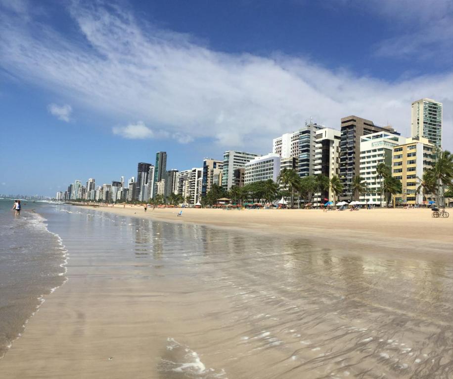 una spiaggia sabbiosa con edifici sullo sfondo e l'oceano di Extraordinary Seafront Apartment a Recife