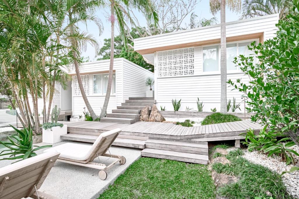 ein Haus mit Garten, Holzterrasse und Stuhl in der Unterkunft Bask & Stow I Luxe Guesthouse in Byron Bay