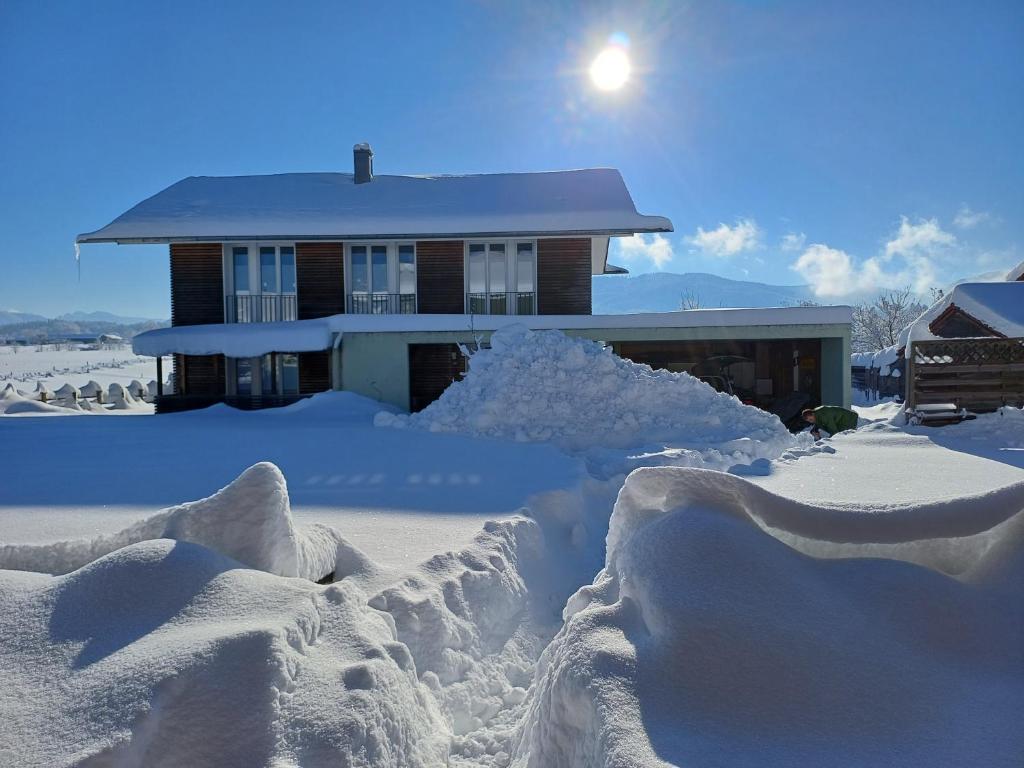 une maison recouverte de neige devant une maison dans l'établissement Komplettes Wellnesshaus mit freiem Blick, à Waakirchen
