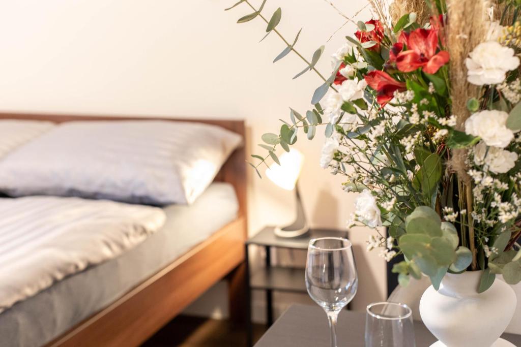 a bedroom with a bed and a table with a vase with flowers at Penzion u Nás u Hospůdky in Žatec