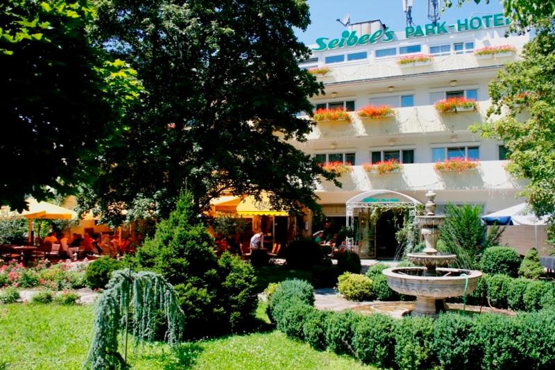 ein Hotel mit einem Brunnen inmitten eines Gartens in der Unterkunft Seibel's Park Hotel in München