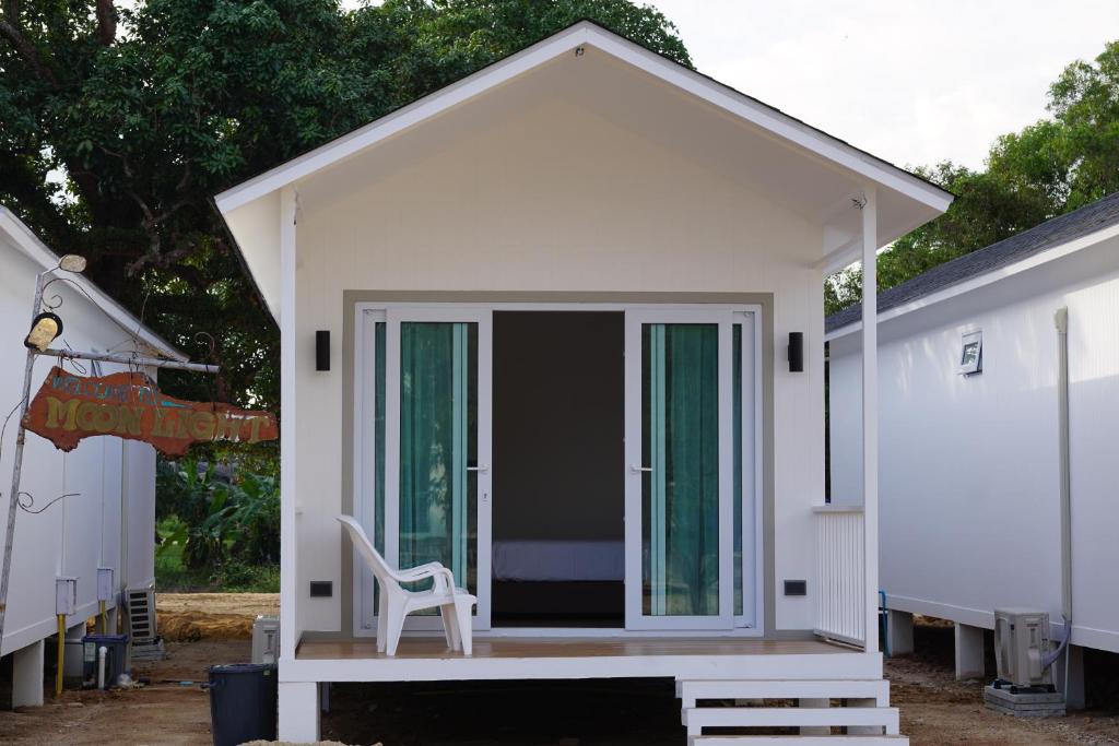 a small white house with a chair on the porch at Travellers Palm in Koh Phangan