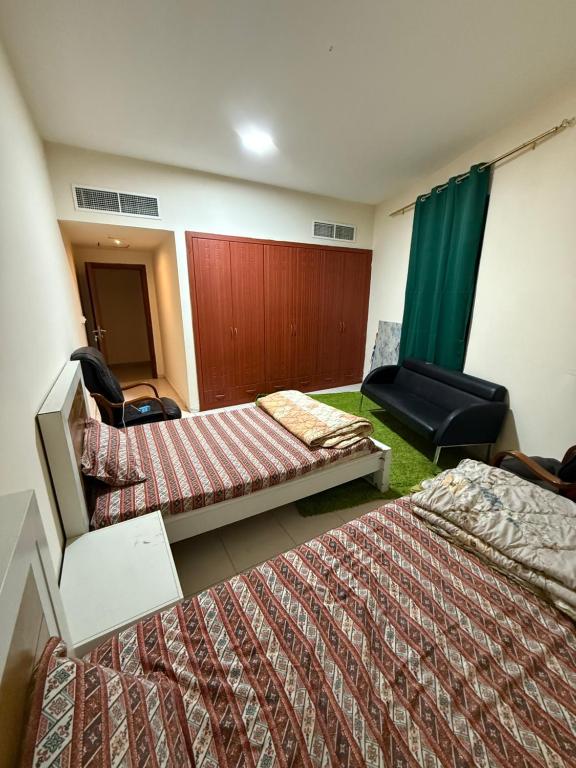 ein Hotelzimmer mit zwei Betten und einem Stuhl in der Unterkunft Ajman Rashdiya 1 in Ajman 
