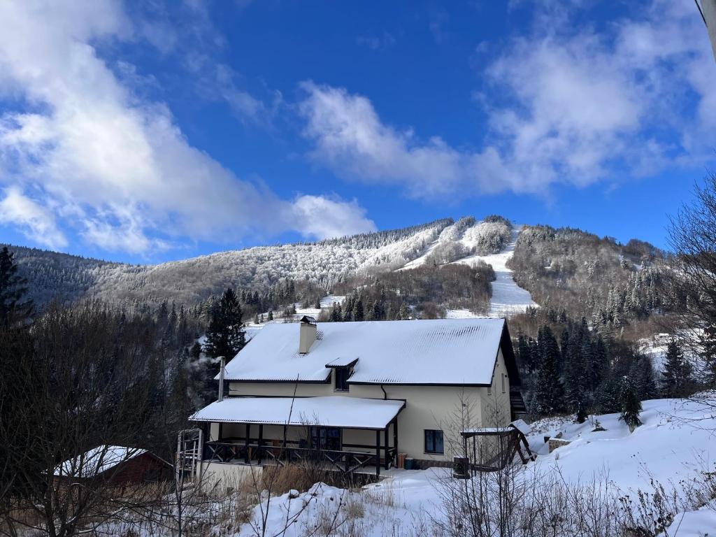 una casa ricoperta di neve di fronte a una montagna di Hillside a Slavske