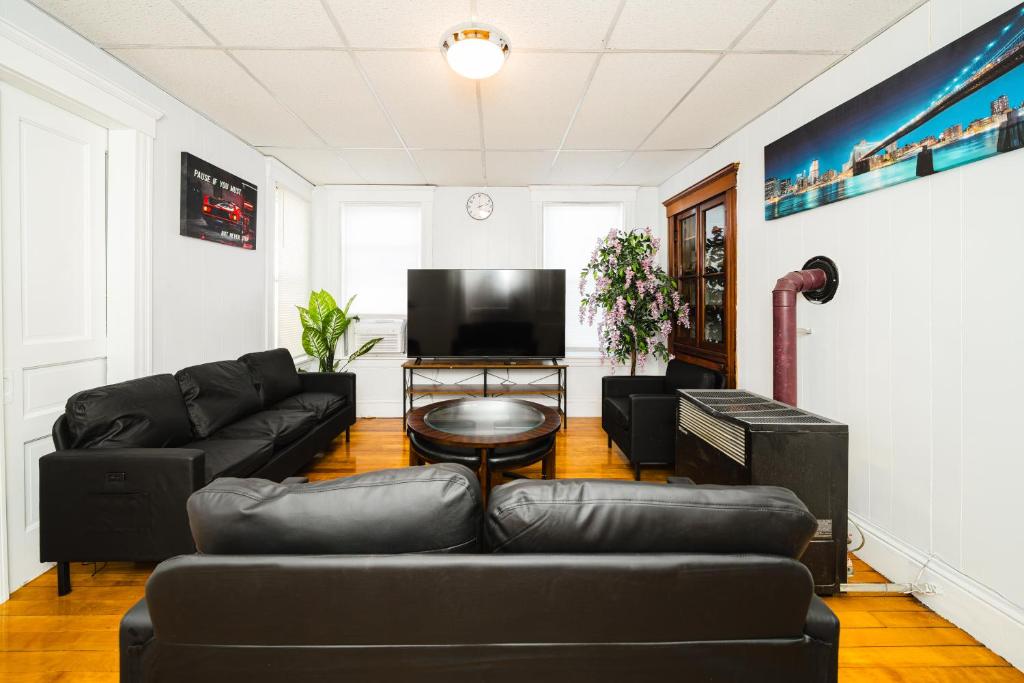 a living room with black furniture and a flat screen tv at Cozy 3BR Worcester 1st-floor Apt, Pet-Friendly, Near Clark University, Free Parking 4-1 in Worcester