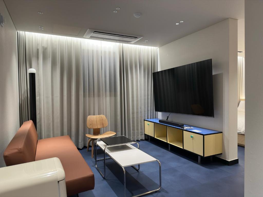 a living room with a couch and a flat screen tv at Fritta Hotel in Suwon
