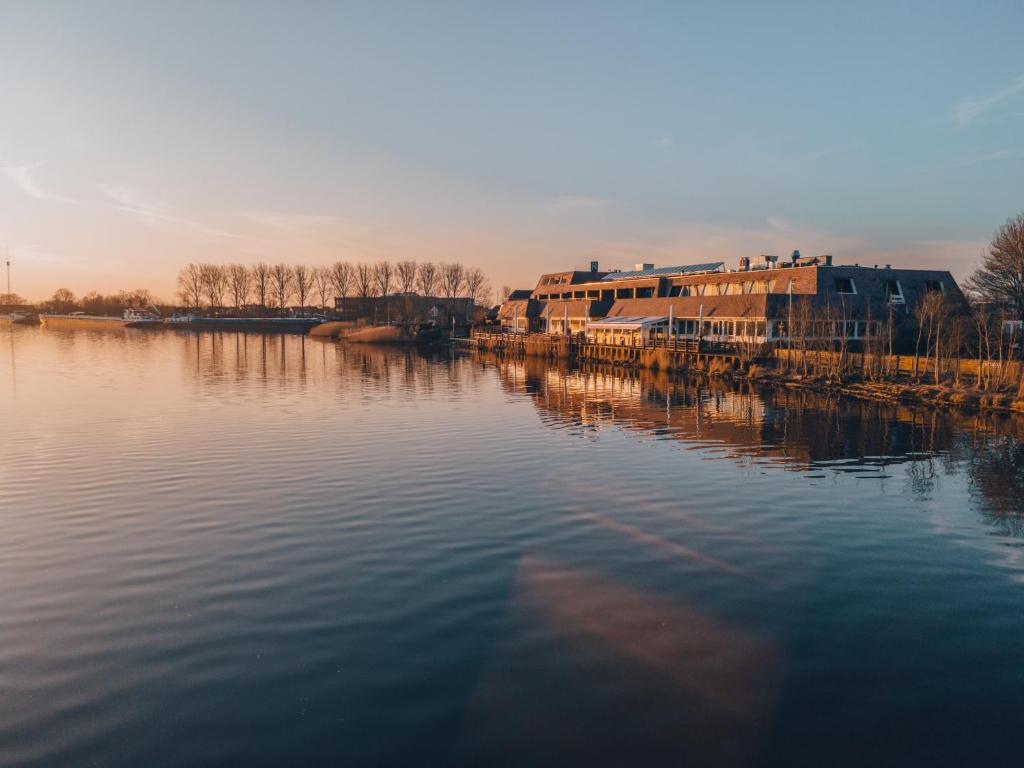 a view of a river with houses and buildings at Hotel Zwartewater in Zwartsluis