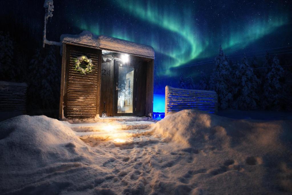 a cabin in the snow with the northern lights at Aurora Igloo Village Ylläs - Hot Tub in Ylläsjärvi