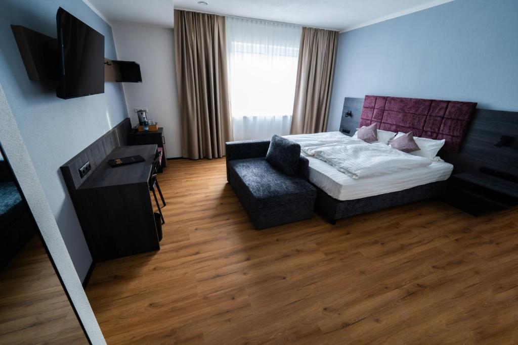 a hotel room with a bed and a chair at PEN Smart Hotel in Türkheim