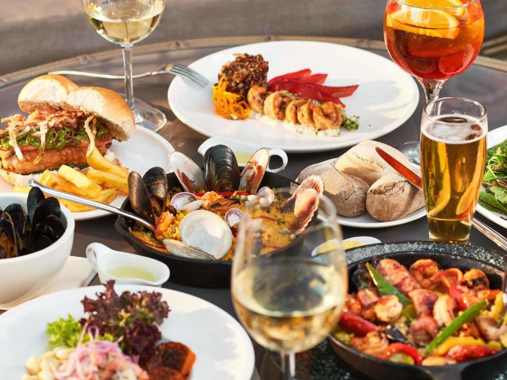 una tavola con piatti di cibo e bicchieri di vino di Pullman Vina del Mar San Martin a Viña del Mar