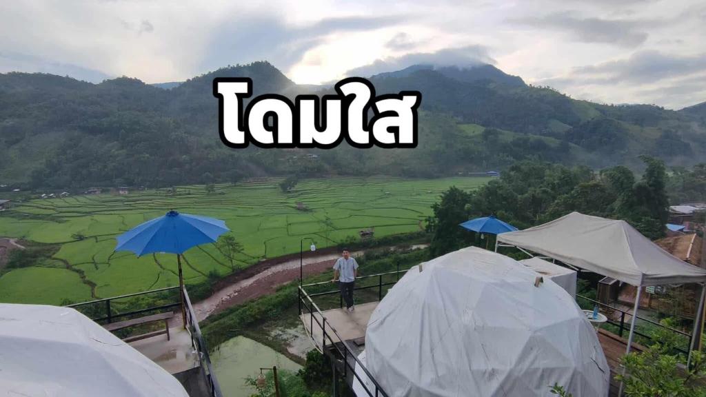 a man standing on a balcony with a view of a field at เวนิสบ้านเวร โดมใส in Ban Khun Nam Nan