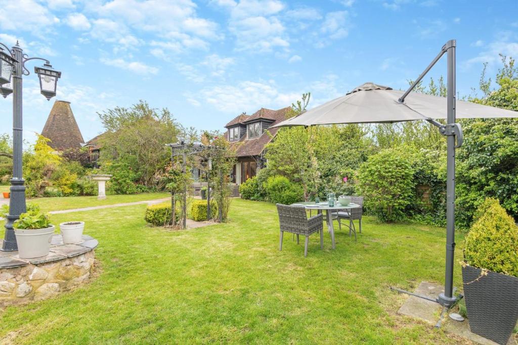 einen Garten mit einem Sonnenschirm, einem Tisch und Stühlen in der Unterkunft 1 Bed in Pluckley oc-a29239 in Smarden