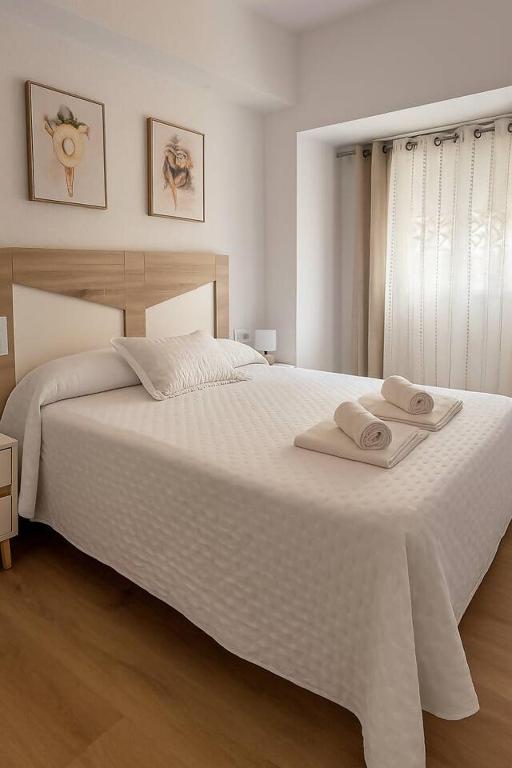 a bedroom with a large white bed with towels on it at Alojamiento Baeza - Leones 9B in Baeza