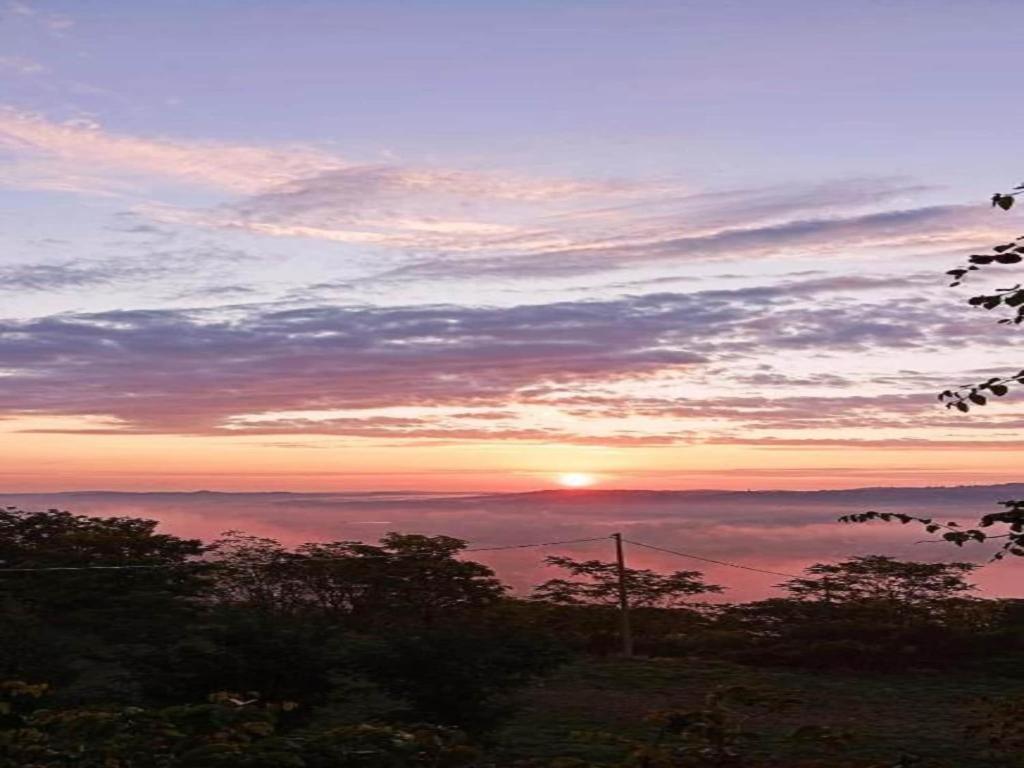 een uitzicht op een zonsondergang met de zon in de horizon bij Apartment in a farmhouse with 2 swimming pools in Cagli