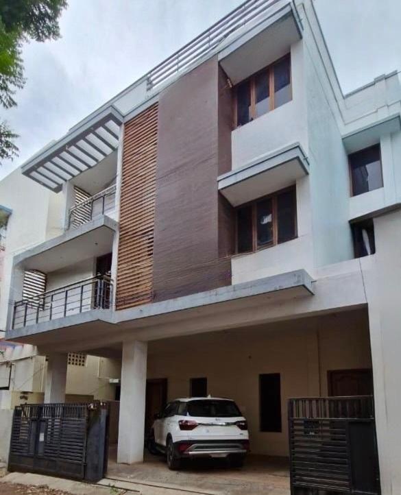 a white car parked in front of a building at Carmel Stay in Madurai