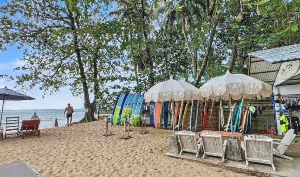 een strand met stoelen, parasols en surfplanken bij Khao Lak - Loft Suite with 2 king size beds, bathroom with bathtub in Khao Lak