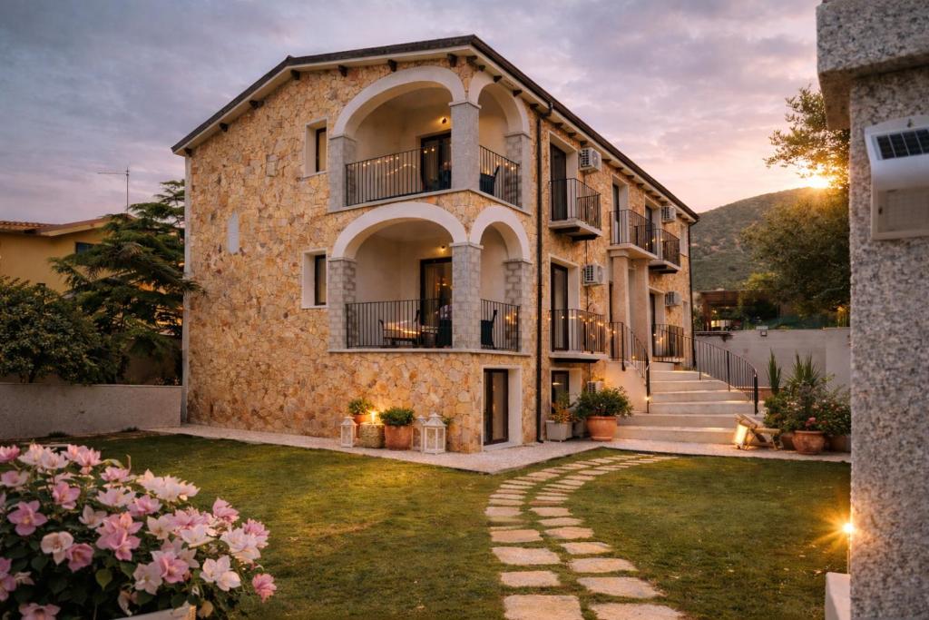 - un grand bâtiment en pierre avec une pelouse dans l'établissement residence Sant'Anna i4MORI, à SantʼAnna Arresi