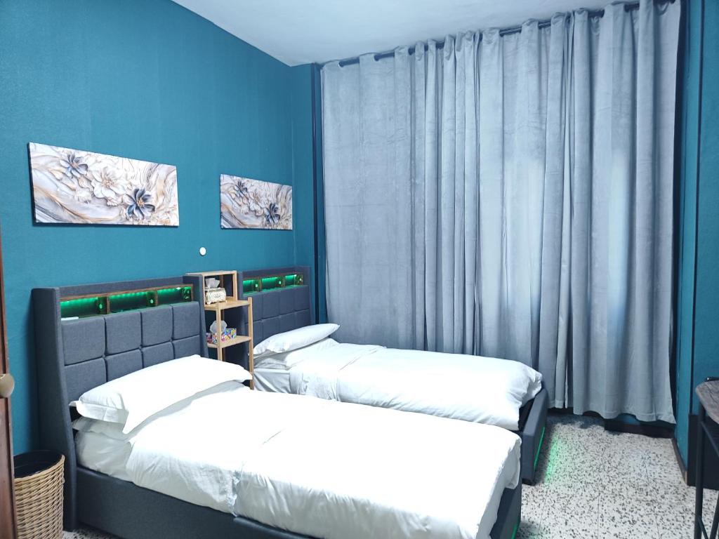 twee bedden in een kamer met blauwe muren bij FARISHTAs house two bedroom apartment in Corsico