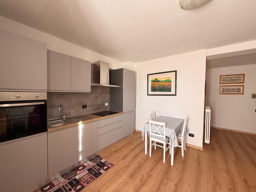 une cuisine avec des armoires blanches et une table avec des chaises dans l'établissement Monolocale a Molveno, à Molveno