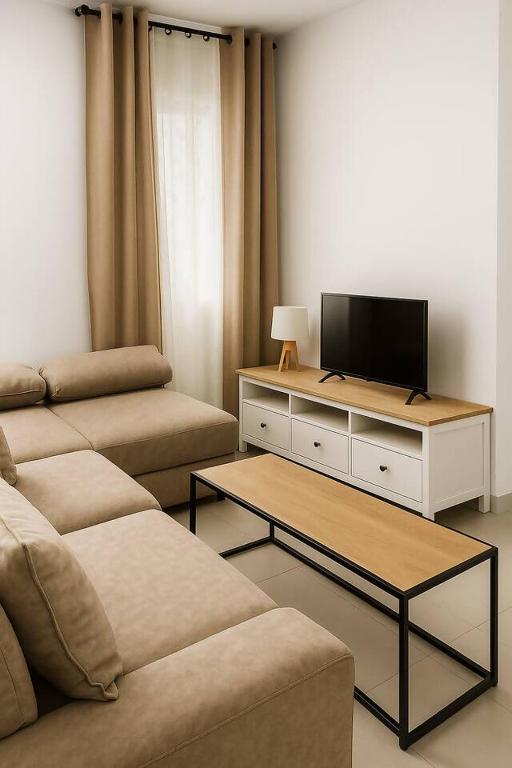 a living room with a couch and a flat screen tv at Alojamiento Baeza California 4B in Baeza