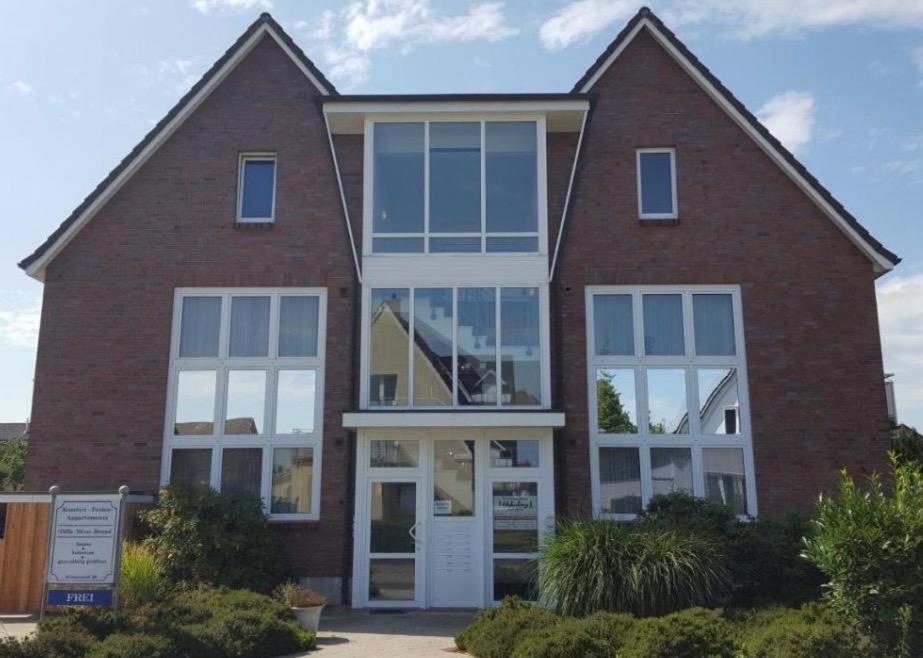 een stenen huis met witte deuren en ramen bij Villa Döser Strand Wohnung 5 in Cuxhaven