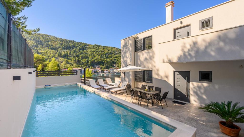 a swimming pool next to a building with a table and chairs at Villa Dida Bozo by Villas Guide in Blace