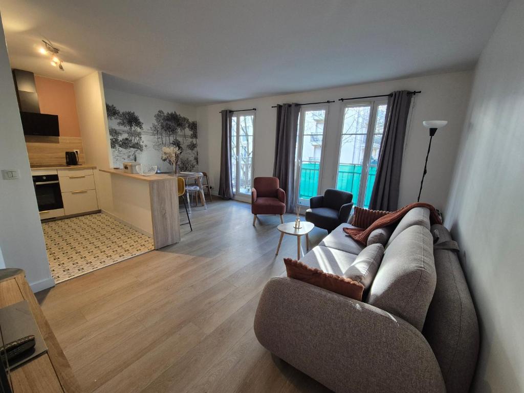 een woonkamer met een bank en een keuken bij Appartement cosy près du RER in Chessy