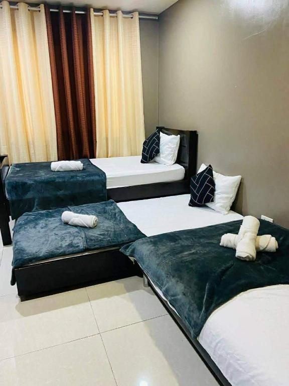 three beds in a hotel room with two bedsitures at The Highland Condotel in Baguio