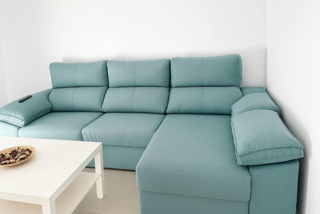 a blue couch in a living room with a table at Alojamiento Baeza California 2B in Baeza