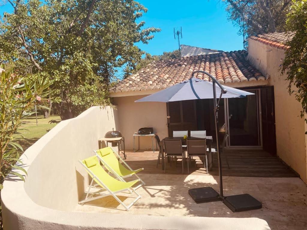 a patio with a table and chairs and an umbrella at Maison en corse in Santa-Maria-Poggio