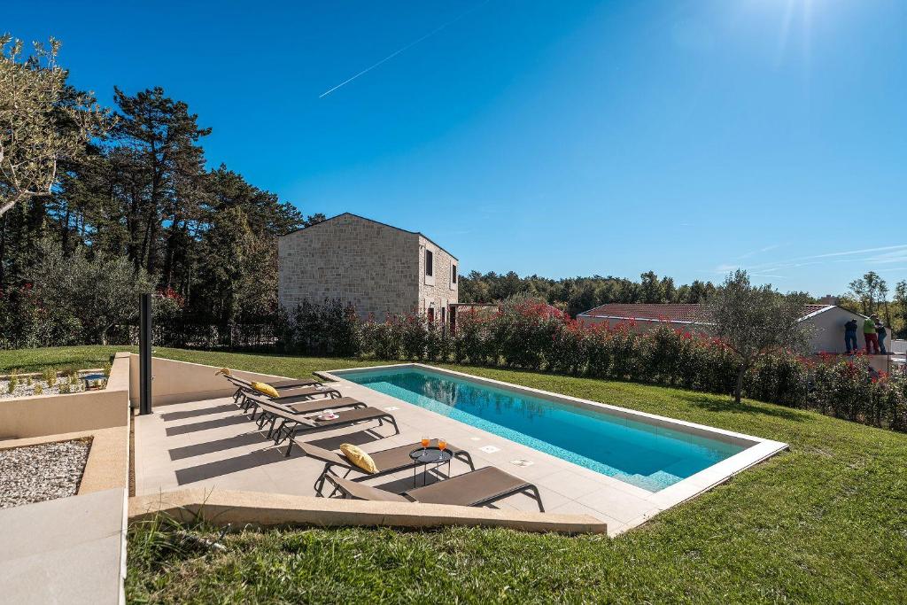 - une piscine avec des chaises longues à côté d'une cour dans l'établissement Mediterrane Steinvilla mit Privatpool, toller Aussicht, starkem WiFi, BBQ, à Majkusi