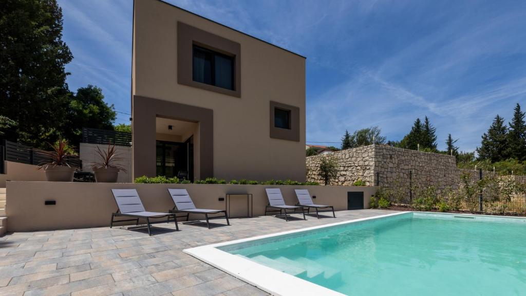 a villa with a swimming pool in front of a house at Villa D Cube by Villas Guide in Duba