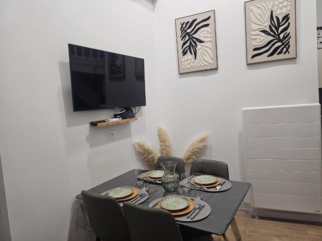 a dining room table with chairs and a television at Le Ptit nid in Château-Gontier
