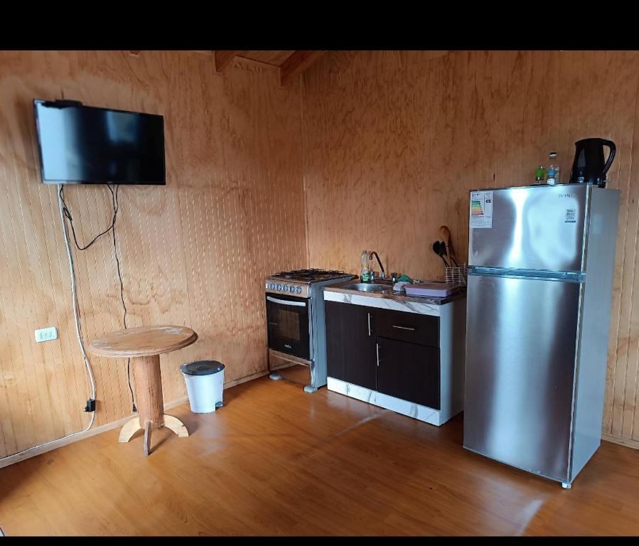 a kitchen with a stainless steel refrigerator and a stool at Cabaña coñico in Coñico