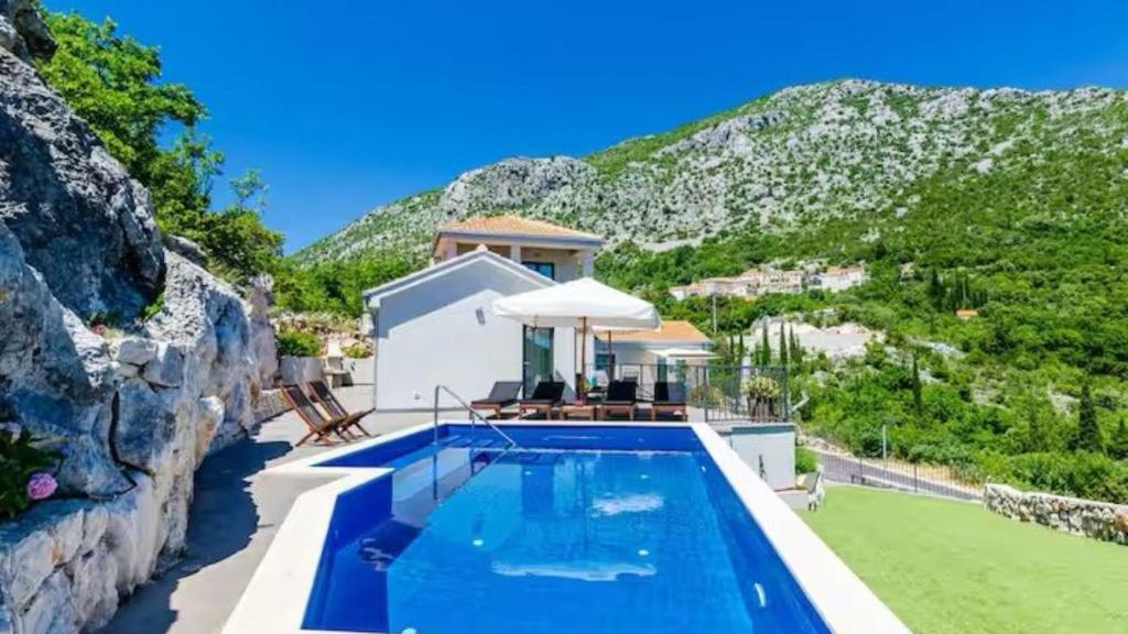 a house with a swimming pool next to a mountain at Villa Bohemia by Villas Guide in Dubrovnik