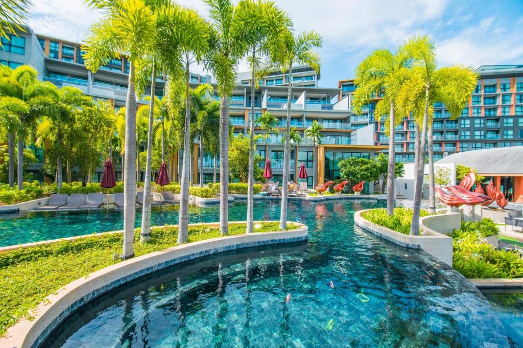 an infinity pool with palm trees in front of a building at Surin Beach View Phuket in Ban Lum Fuang