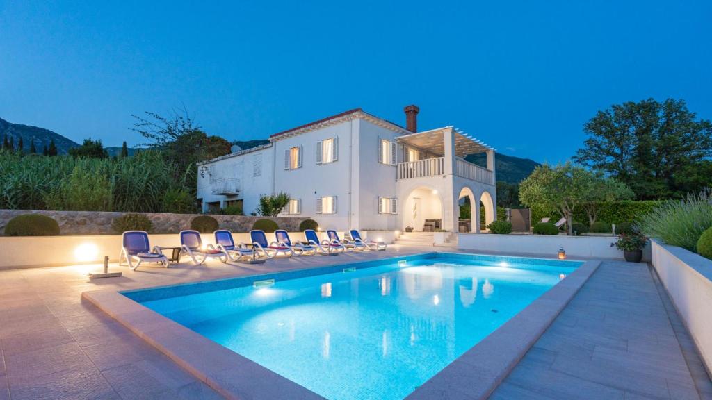 a swimming pool in front of a house at Cypress Paradise by Villas Guide in Dubravka
